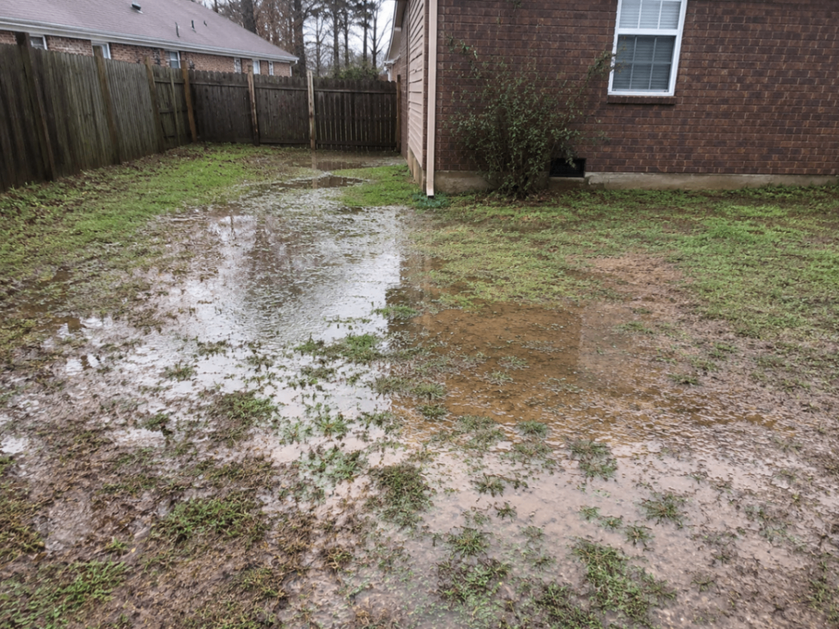 Pooling water beside the rear corner of a brick house